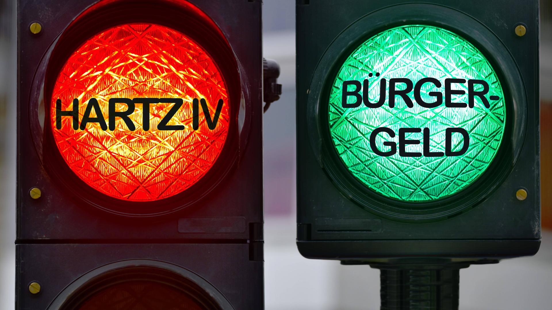 Auf einer roten Ampel steht "Hartz 4". Auf einer grünen Ampel steht "Bürger-Geld".