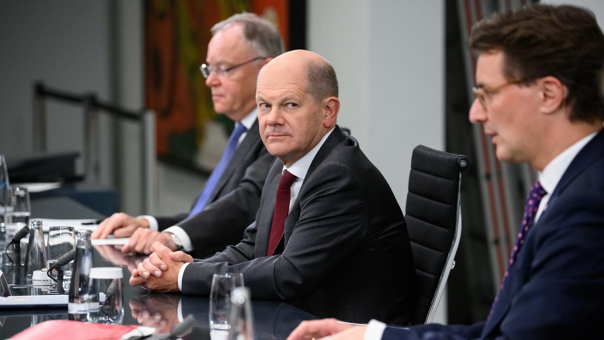 Bundeskanzler Olaf Scholz, platziert links neben Niedersachsens Ministerpräsident Stephan Weil, wirft einen kritischen Blick zum links neben ihm sitzenden NRW-Ministerpräsidenten Hendrik Wüst.
