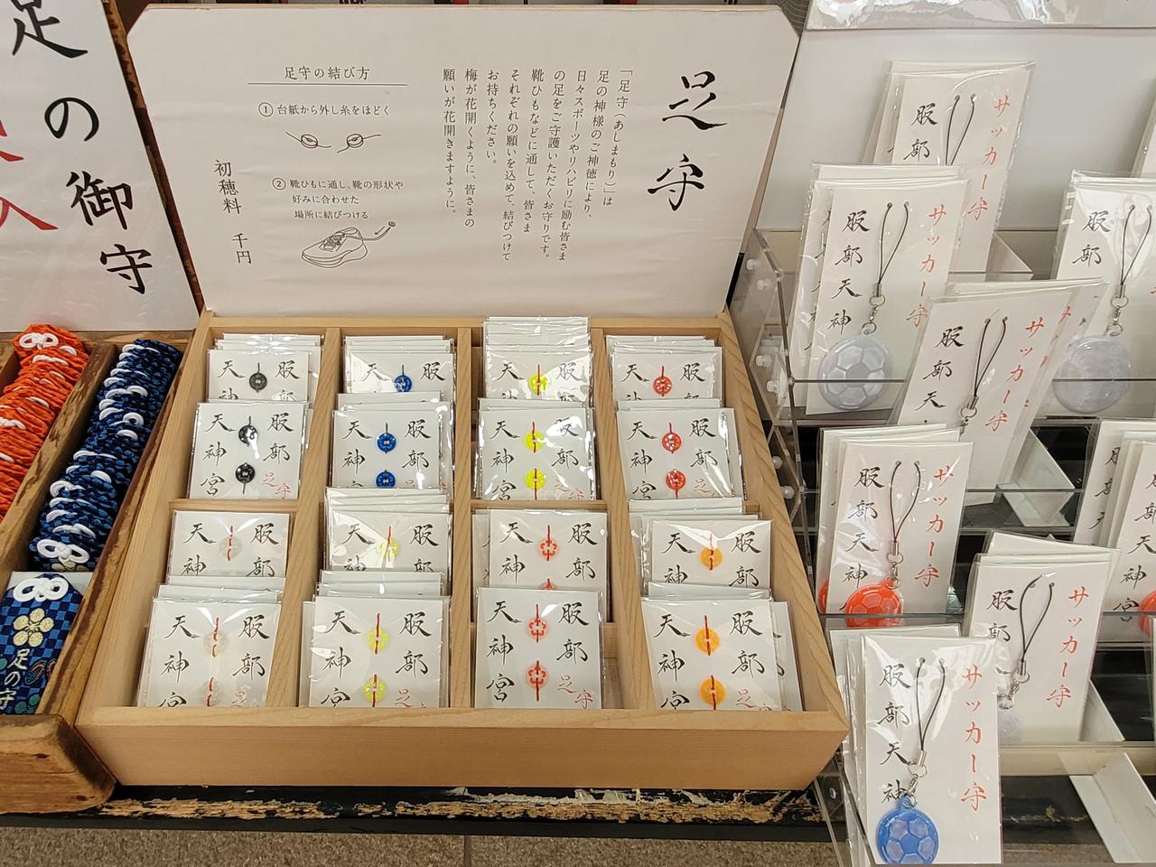 Amulette für Laufsportler, beschrieben mit japanischen Schriftzeichen, werden in einer Holzkiste angeboten. Amulette für Laufsportler, beschrieben mit japanischen Schriftzeichen, werden in einer Holzkiste angeboten.