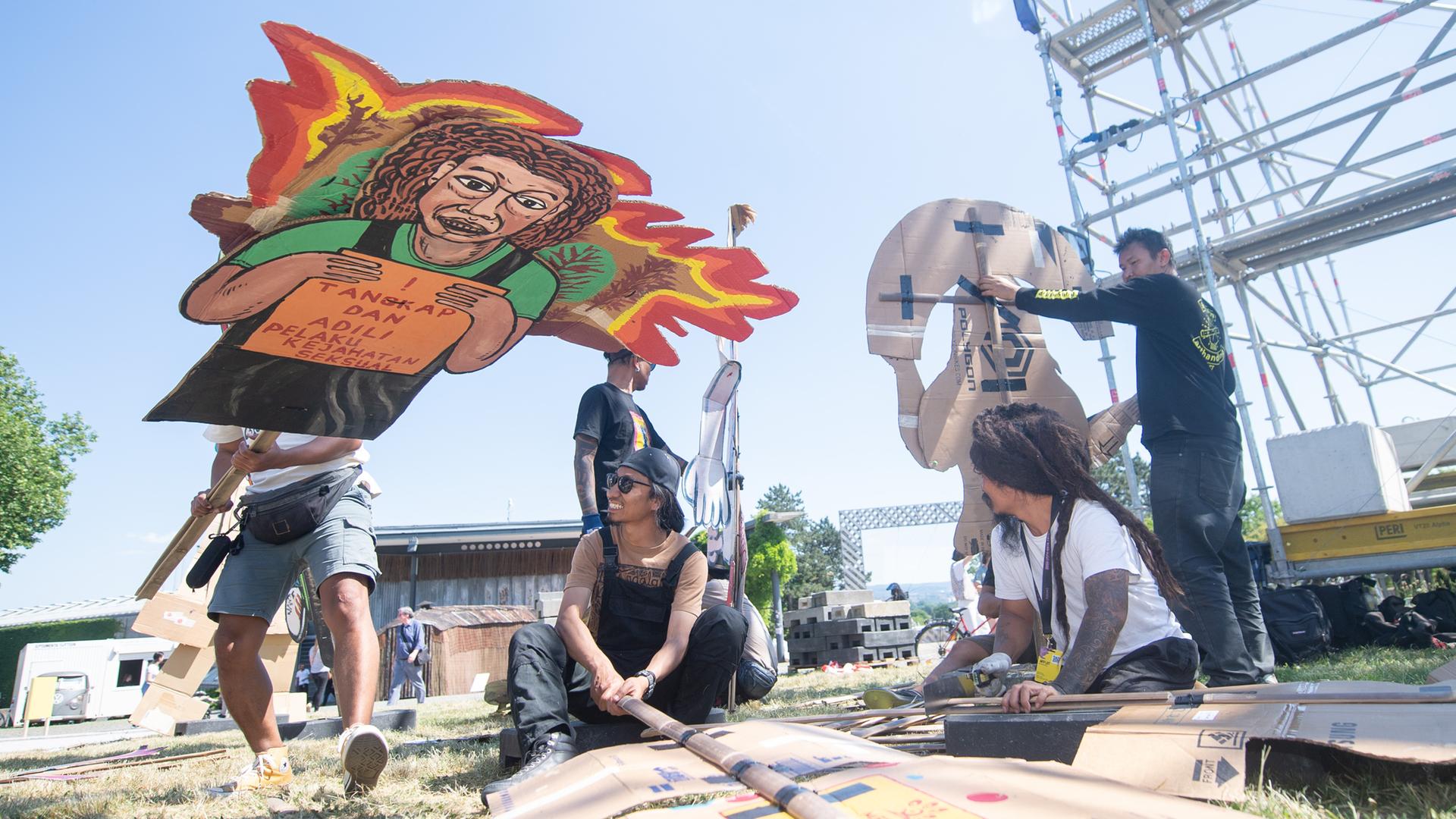 Mitglieder des indonesischen Kunstkollektivs "Taring Padi" stellen überlebensgroße Pappfiguren auf.