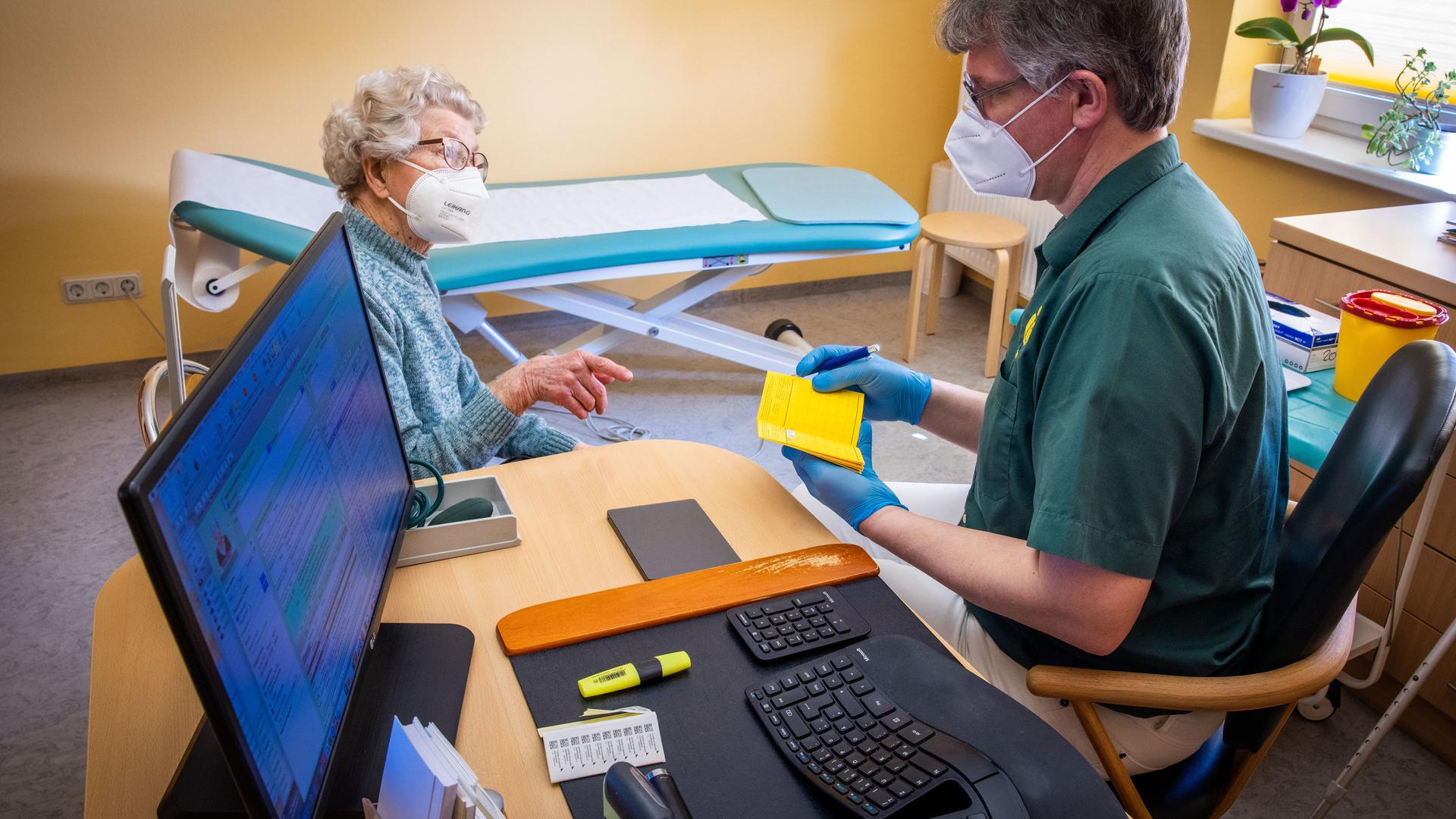 In seiner Hausarztpraxis bespricht Stefan Zutz mit der 95-Jährigen Patientin Ingeborg Ketelhohn die Corona-Impfung, neben ihm auf dem Schreibtisch steht sein PC der alle Patientendaten beinhaltet. In seiner Hausarztpraxis bespricht Stefan Zutz mit der 95-Jährigen Patientin Ingeborg Ketelhohn die Corona-Impfung, neben ihm auf dem Schreibtisch steht sein PC der alle Patientendaten beinhaltet.