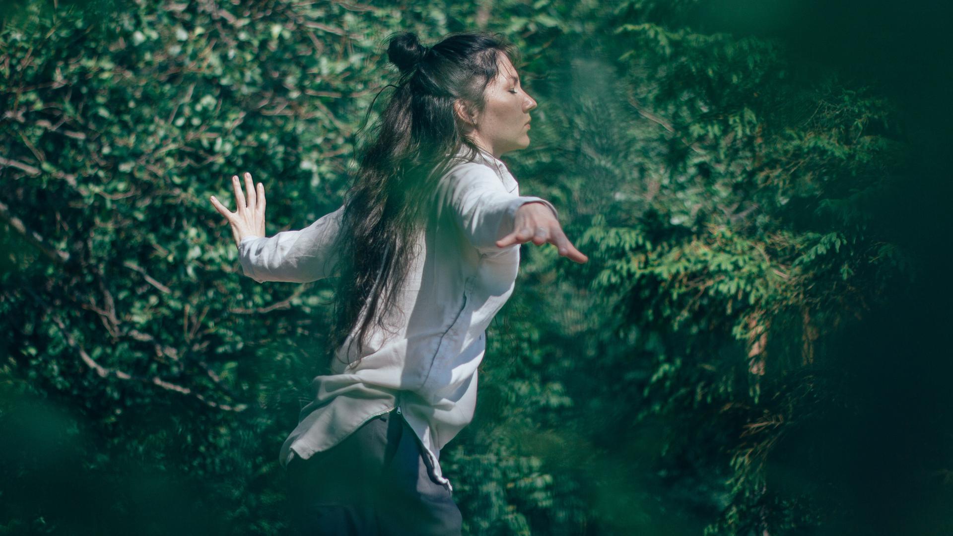 Tanzen - die Spannung zwischen Bei-sich-Sein und Außer-sich-Sein. Zu sehen: Eine Frau tanzt in einem Wald. Tanzen - die Spannung zwischen Bei-sich-Sein und Außer-sich-Sein. Zu sehen: Eine Frau tanzt in einem Wald.