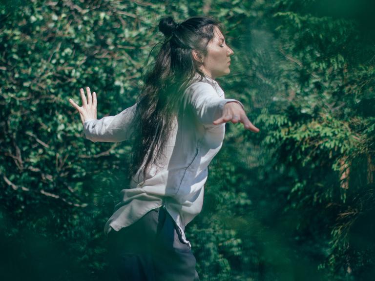 Tanzen - die Spannung zwischen Bei-sich-Sein und Außer-sich-Sein. Zu sehen: Eine Frau tanzt in einem Wald. 