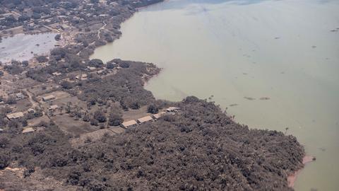 Blick aus einem Flugzeug auf mit Asche bedeckte Häuser und Vegetation auf Tonga Blick aus einem Flugzeug auf mit Asche bedeckte Häuser und Vegetation auf Tonga