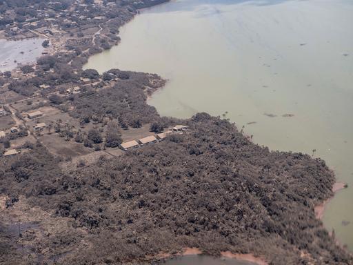 Blick aus einem Flugzeug auf mit Asche bedeckte Häuser und Vegetation auf Tonga Blick aus einem Flugzeug auf mit Asche bedeckte Häuser und Vegetation auf Tonga