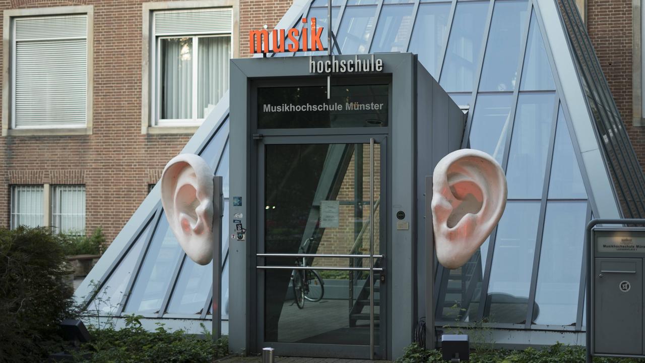An einem Eingang mit modernen Glastüren stehen links und rechts große Ohren zur Dekoration.