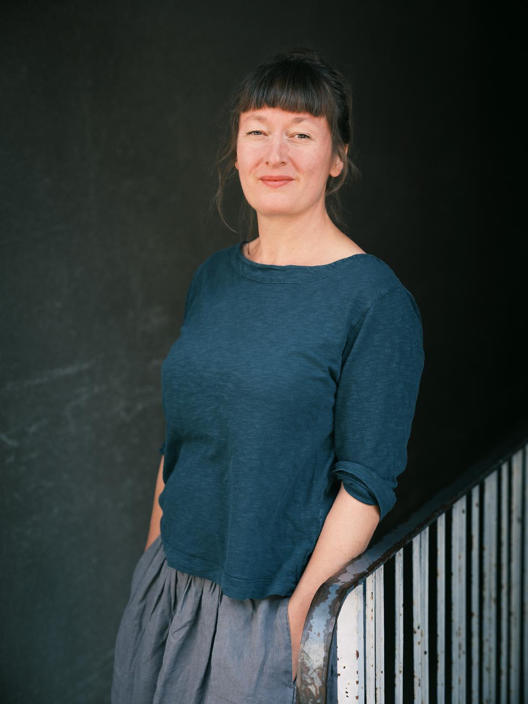 Porträtfoto der Comicautorin Barbara Yelin. Sie trägt ihr braunes Haar hochgesteckt und lehnt an einem Treppengeländer. Porträtfoto der Comicautorin Barbara Yelin. Sie trägt ihr braunes Haar hochgesteckt und lehnt an einem Treppengeländer.