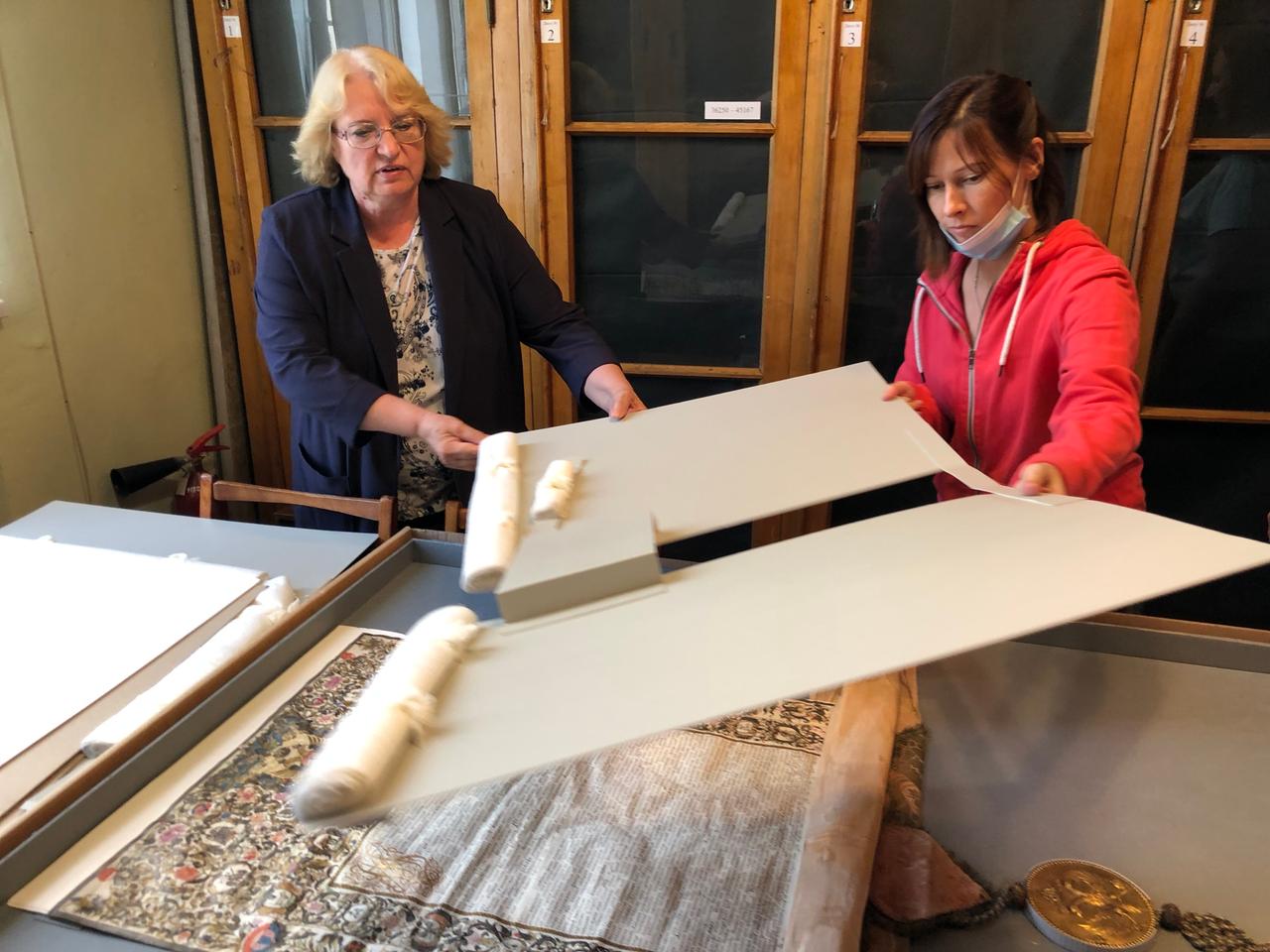 Zarenurkunde in der Wernadskij-Bibliothek. Zwei Frauen packen vorsichtig ein historisches Schriftstück aus. Zarenurkunde in der Wernadskij-Bibliothek. Zwei Frauen packen vorsichtig ein historisches Schriftstück aus.
