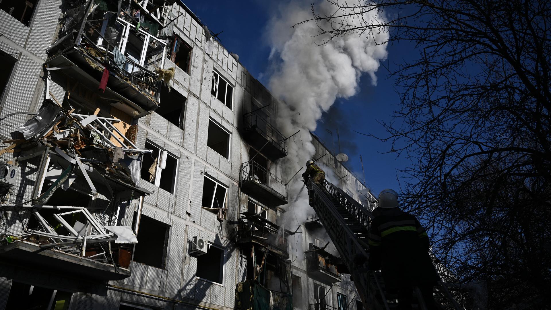 Die Feuerwehr versucht einen Wohnblock mit zerstörten Balkons zu löschen, aus dem eine Rauchwolke hoch aufsteigt. Die Feuerwehr versucht einen Wohnblock mit zerstörten Balkons zu löschen, aus dem eine Rauchwolke hoch aufsteigt.