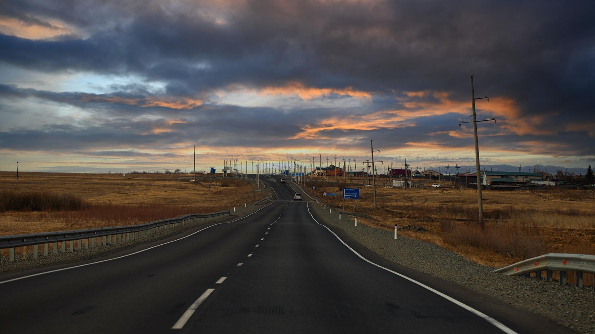Eine Straße führt durch eine Steppe in einer bewölkten Abendstimmung. Eine Straße führt durch eine Steppe in einer bewölkten Abendstimmung.