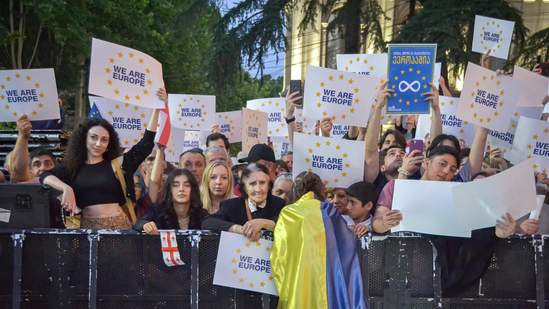 Menschen halten Plakate in die Höhne bei einer Demonstration in Tiflis. 