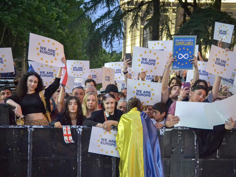 Menschen halten Plakate in die Höhne bei einer Demonstration in Tiflis. 