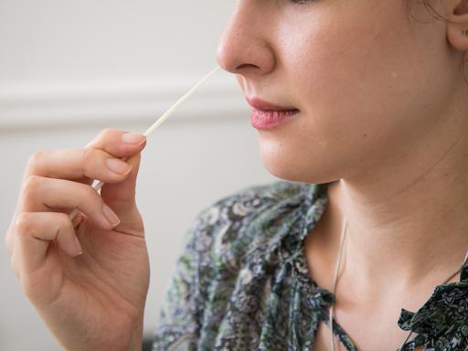Eine Frau führt ein Teststäbchen in die Nase (gestellte Szene)