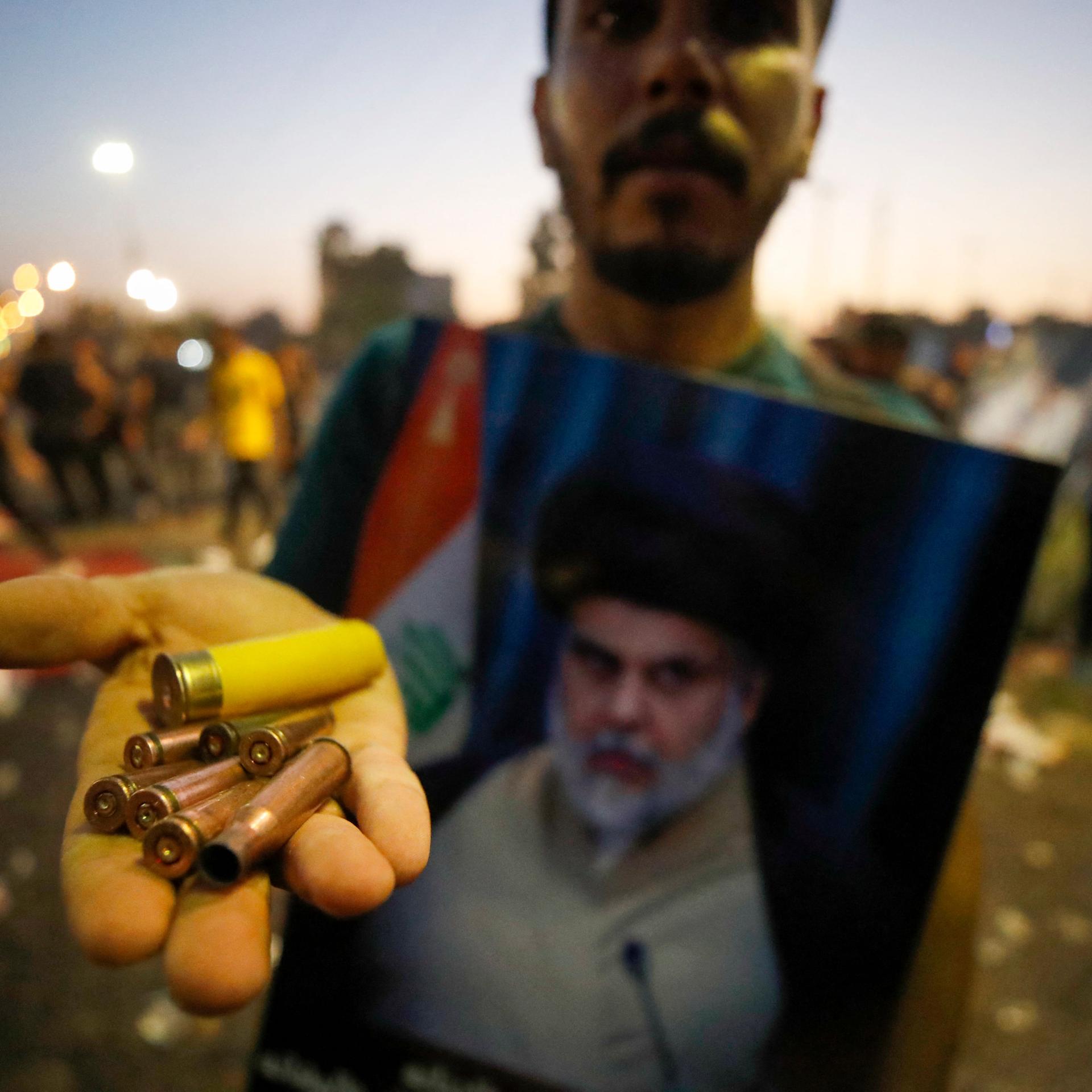 Ein Anhänger von al-Sadr mit einem Bild des Schiitenführers zeigt Patronenhülsen.