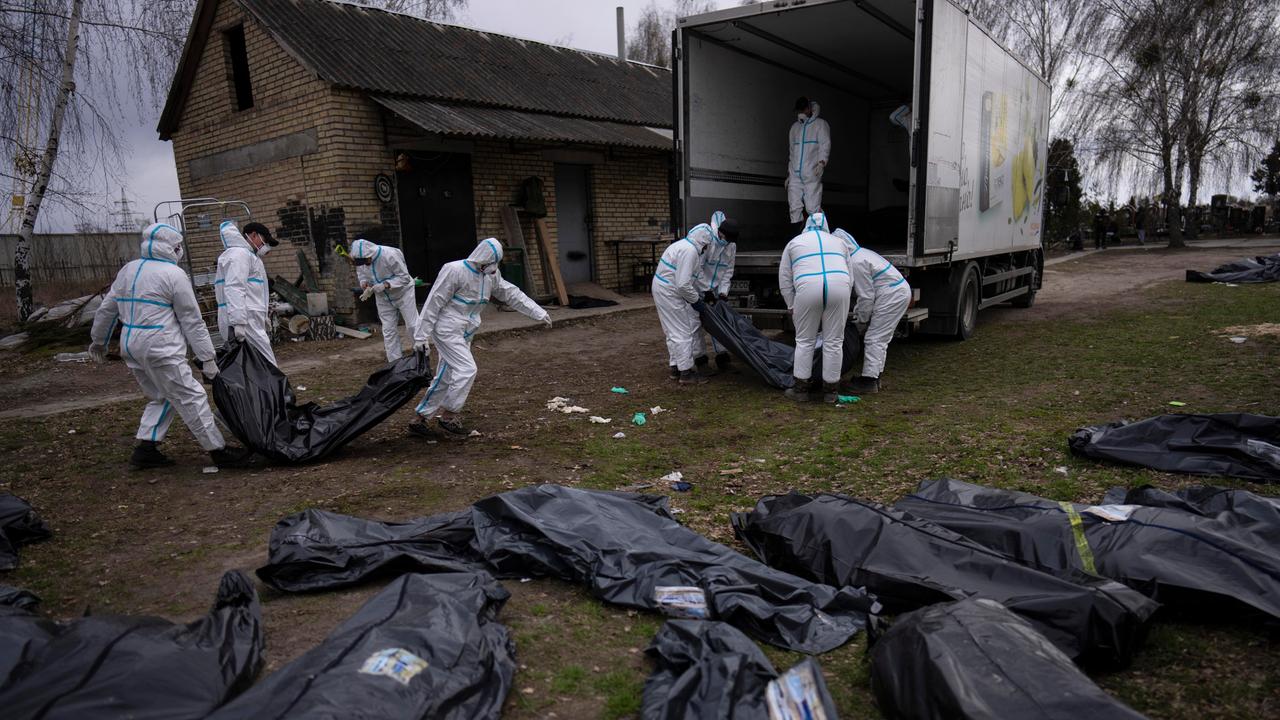 Freiwillige laden in Plastiksäcke gehüllte Leichen auf einen Lastwagen.