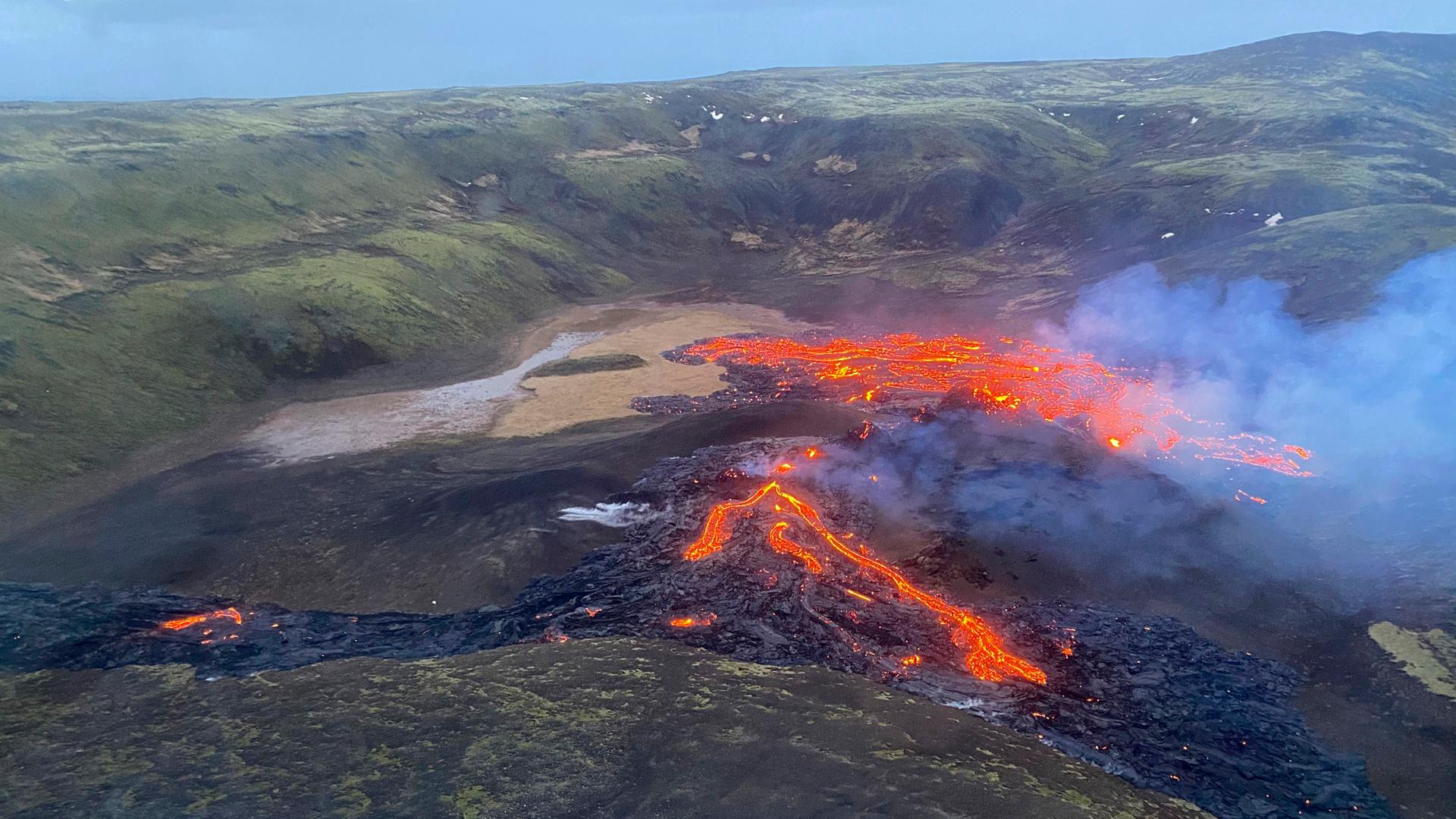 Eine Luft-Aufnahme zeigt, wie Lava aus dem Vulkan Fagradalsfjall fließt und Rauch aufsteigt.