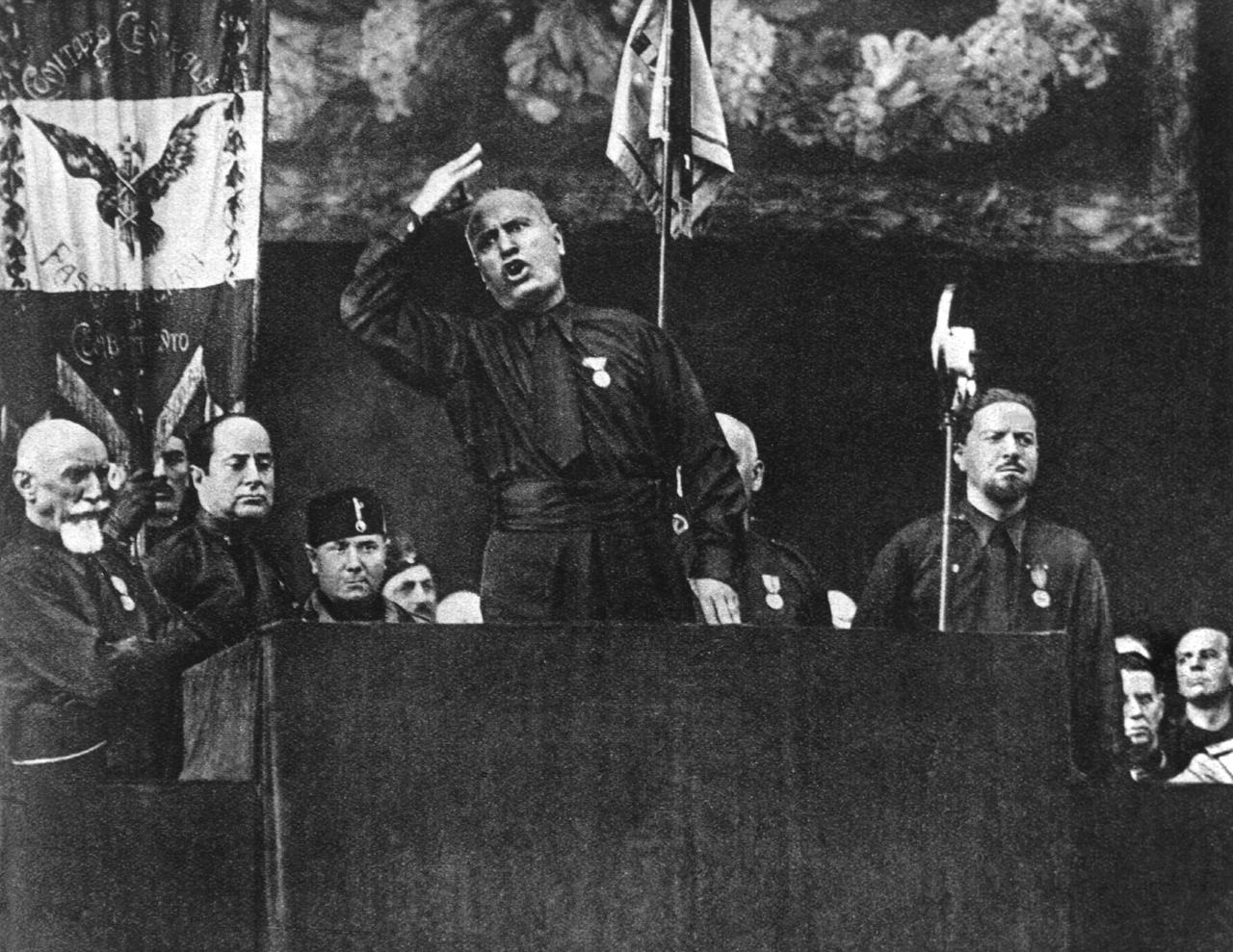 Der "Duce" Benito Mussolini auf der Piazza Venezia in Rom 1932 während einer Ansprache zur Feier der zehnjährigen faschistischen Machtergreifung. Mit dem "Marsch auf Rom" am 28. Oktober 1922 und der am 29. Oktober von König Viktor Emanuel III. an Benito Mussolini übertragenen Regierungsgewalt begann in Italien die Phase des Faschismus. Bis 1928 schaltete Mussolini die anderen Parteien aus und errichtete eine Ein-Mann-Diktatur. Zunächst in machtpolitischer Rivalität zu Deutschland, verzichtete Italien durch eigenes Expansionsstreben auf die traditionelle Gleichgewichtspolitik und ging ein Bündnis mit Hitler-Deutschland ein, das 1940 zum Eintritt Italiens an der Seite Deutschlands im II. Weltkrieg und schlieÃlich zur Niederlage und dem Ende des Faschismus führte. Der "Duce" Benito Mussolini auf der Piazza Venezia in Rom 1932 während einer Ansprache zur Feier der zehnjährigen faschistischen Machtergreifung. Mit dem "Marsch auf Rom" am 28. Oktober 1922 und der am 29. Oktober von König Viktor Emanuel III. an Benito Mussolini übertragenen Regierungsgewalt begann in Italien die Phase des Faschismus. Bis 1928 schaltete Mussolini die anderen Parteien aus und errichtete eine Ein-Mann-Diktatur. Zunächst in machtpolitischer Rivalität zu Deutschland, verzichtete Italien durch eigenes Expansionsstreben auf die traditionelle Gleichgewichtspolitik und ging ein Bündnis mit Hitler-Deutschland ein, das 1940 zum Eintritt Italiens an der Seite Deutschlands im II. Weltkrieg und schlieÃlich zur Niederlage und dem Ende des Faschismus führte.