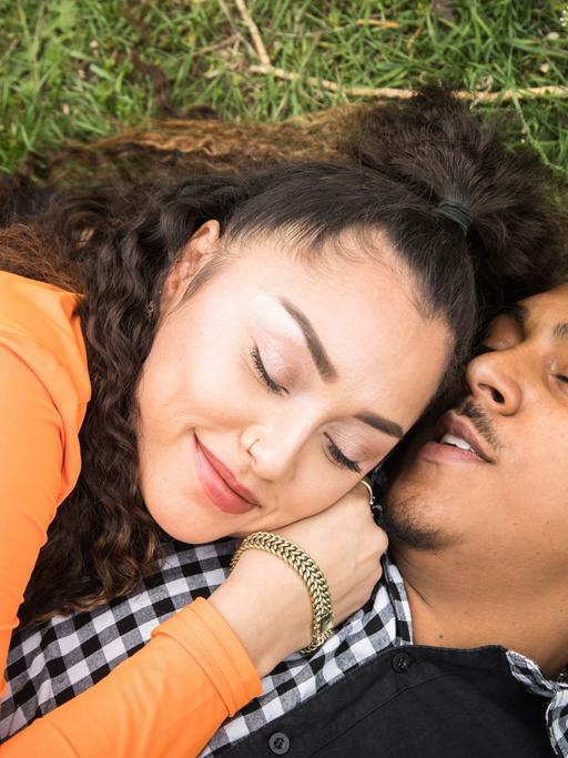 ILLUSTRATION - Ein junges Paar liegt am 05.05.2022 in einem Park in Berlin verliebt auf einer Decke (gestellte Szene). Foto: Christin Klose || Modellfreigabe vorhanden