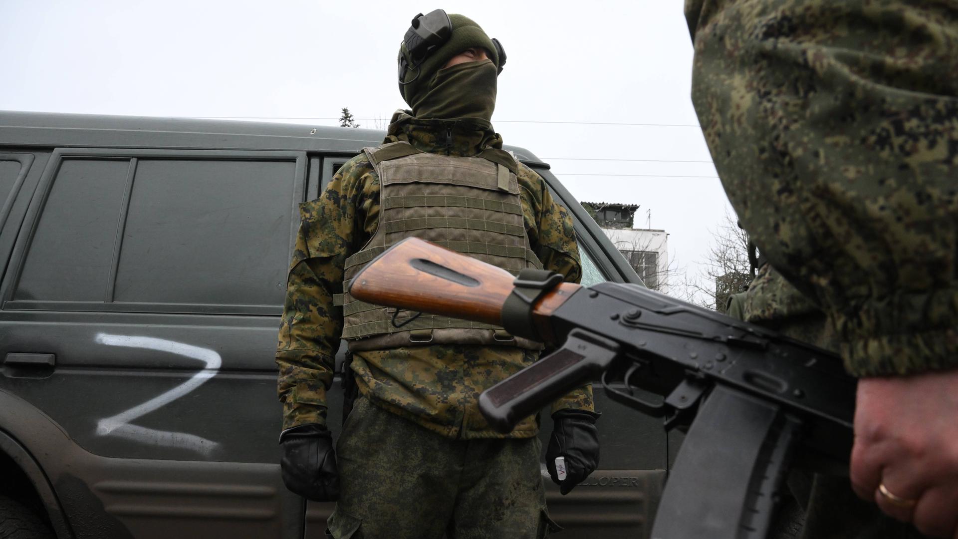 Russisches Militärfahrzeug mit dem Buchstaben "Z". Zwei uniformierte Soldaten stehen neben dem Fahrzeug.