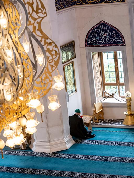 Eine Person liest in der Sehitlik-Moschee in Berlin-Neukölln im Koran. Der Fastenmonat beginnt offiziell an diesem Mittwochabend. Tagsüber verzichten gläubige Muslime auf Essen und Trinken. Erst nach Sonnenuntergang trifft man sich zum gemeinsamen Fastenbrechen. Besonders ist in diesem Jahr, dass sich Ramadan, die christliche Fastenzeit und Ostern sowie das jüdische Pessach überschneiden.