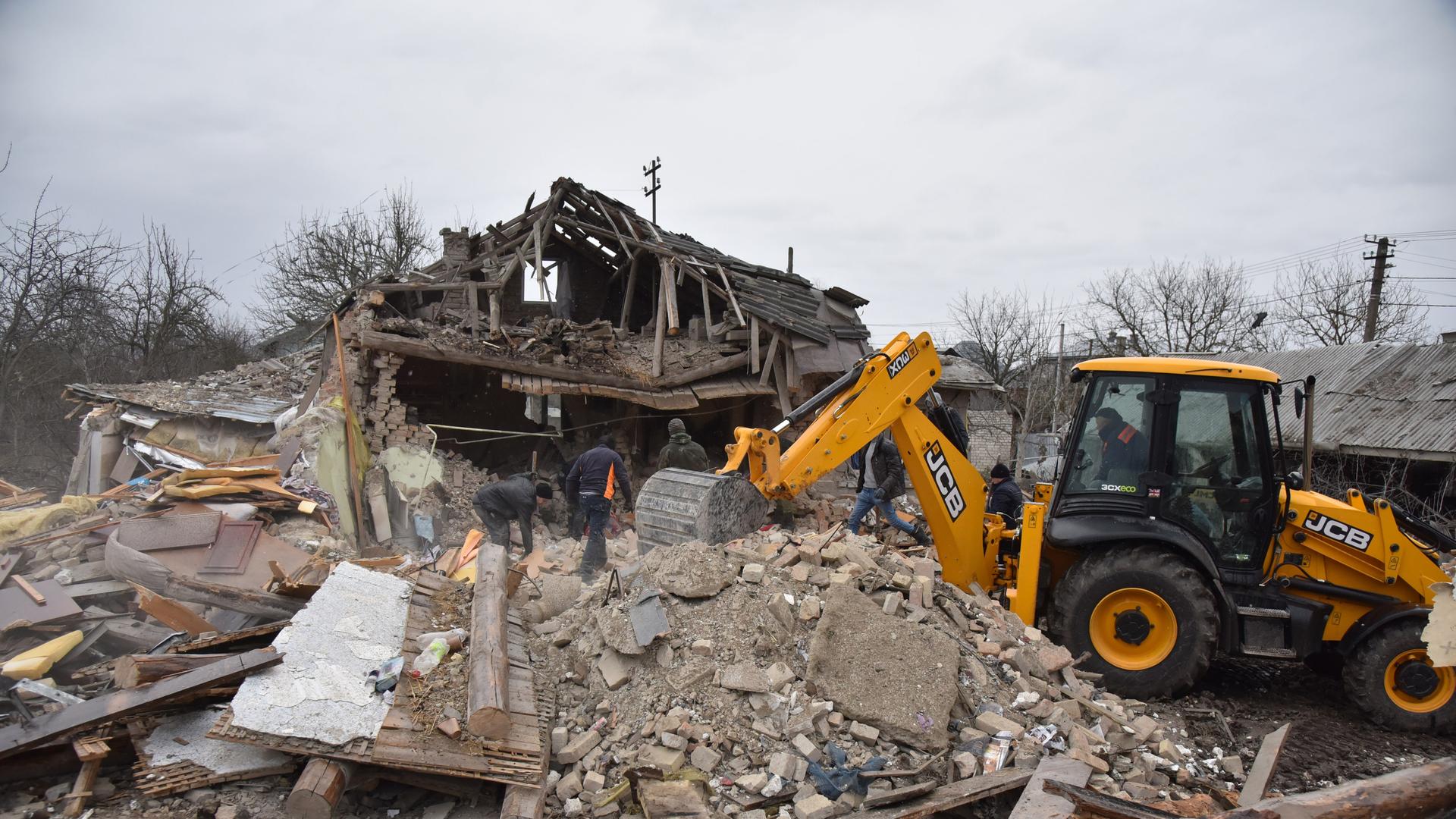 Mit einem Bagger werden die Überreste zweier zerstörter Wohnhäuser in einem Dorf bei Lviv in der Westukraine beräumt. Die Häuser wurden am 9. März 2023 von Raketen getroffen, fünf Menschen wurden getötet.