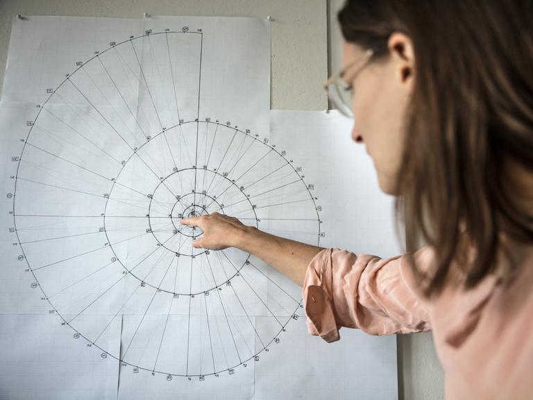 Catherine Lamb weist mit dem Zeigefinger auf eine spiralförmige Grafik.