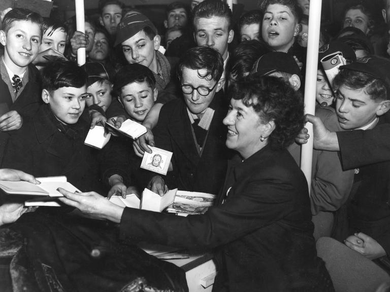 Die britische Kinderbuchautorin Enid Blyton inmitten von Kindern bei einer Autogrammstunde in London 1953.
