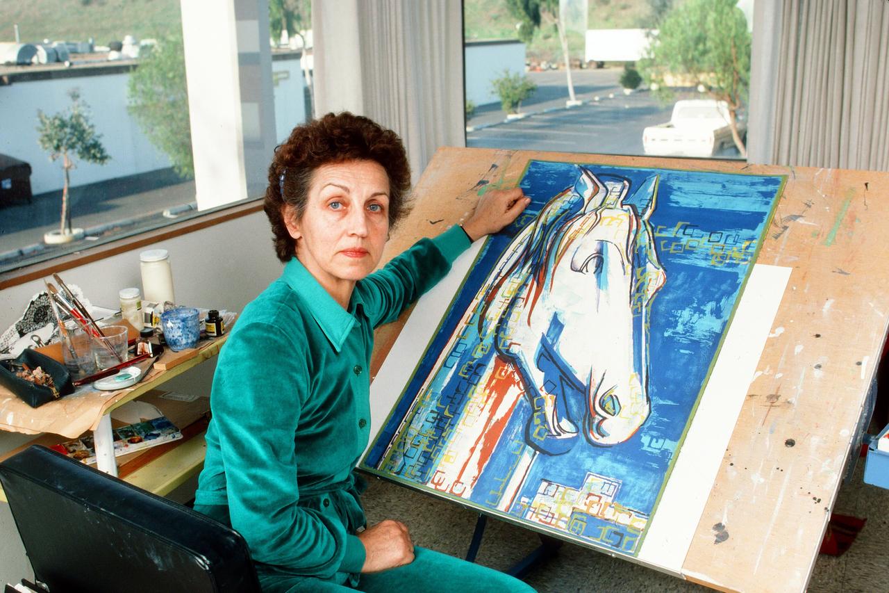 Françoise Gilot sitzt neben einem Gemälde mit der Darstellung eines blauen Pferdes am Tisch. Françoise Gilot sitzt neben einem Gemälde mit der Darstellung eines blauen Pferdes am Tisch.