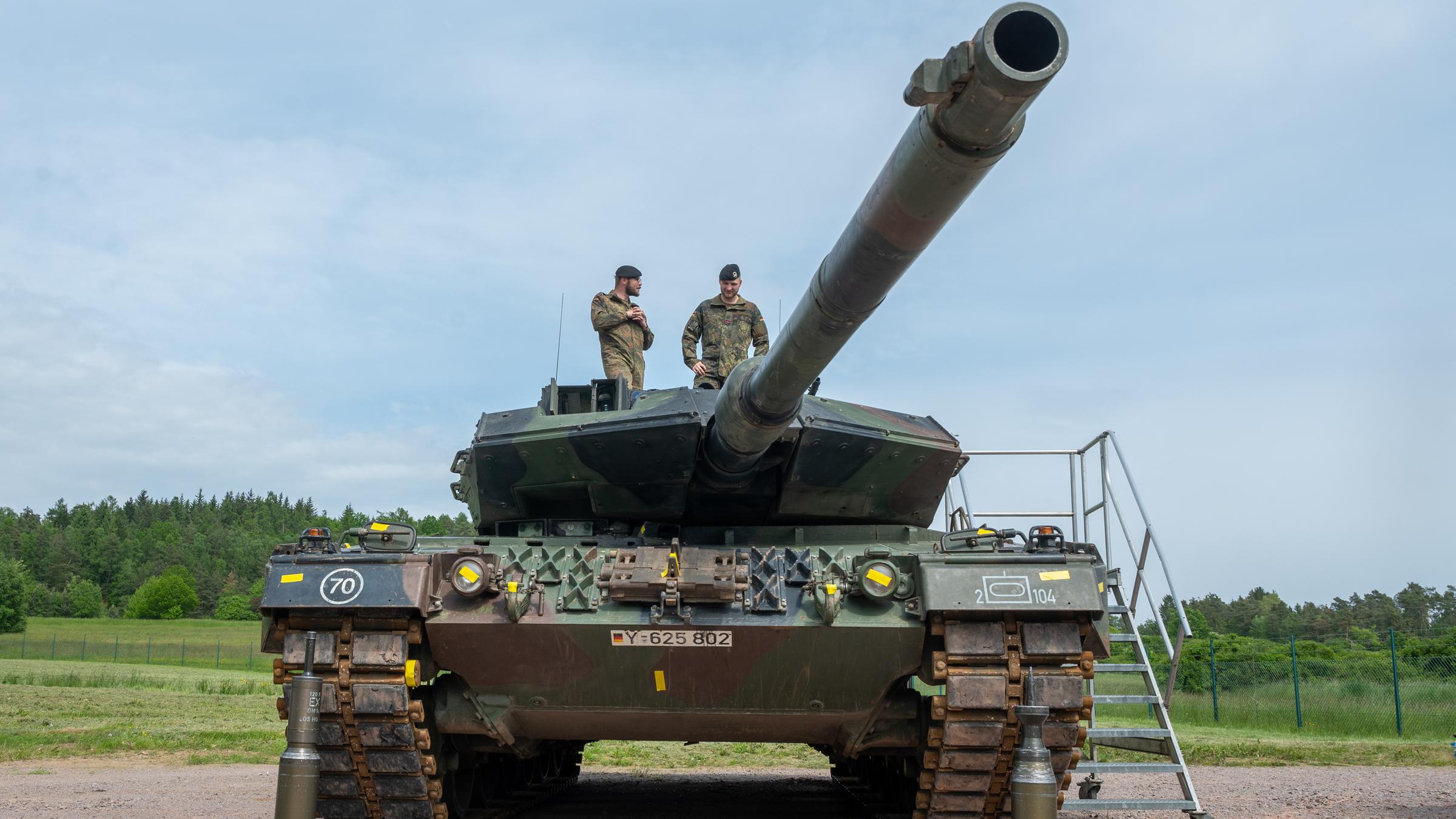 Ein Kampfpanzer auf dem zwei Soldaten stehen. Vor dem Fahrzeug steht Munition. 