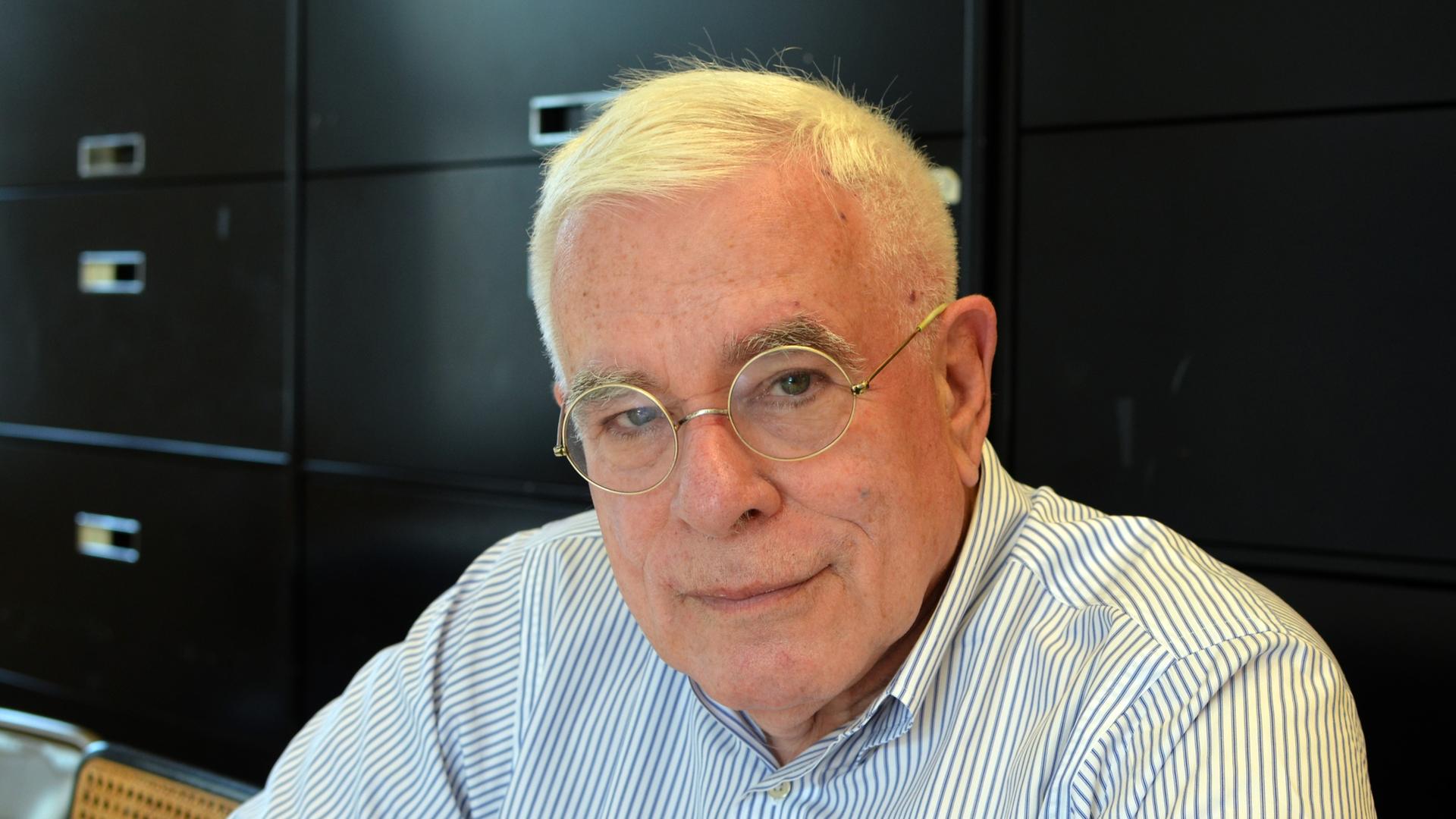Der Architekt Peter Eisenman trägt ein gestreiftes Hemd und sitzt in seinem Büro vor einem schwarzen Schrank Der Architekt Peter Eisenman trägt ein gestreiftes Hemd und sitzt in seinem Büro vor einem schwarzen Schrank