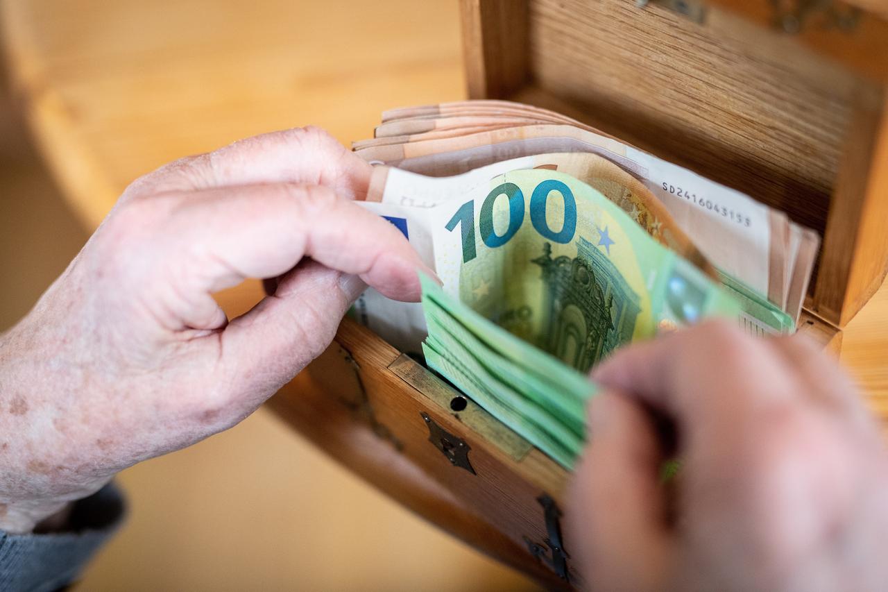 Eine über 90-jährigen Dame zählt mehrere hundert Euro in Geldscheinen in einer kleinen Schatztruhe ab