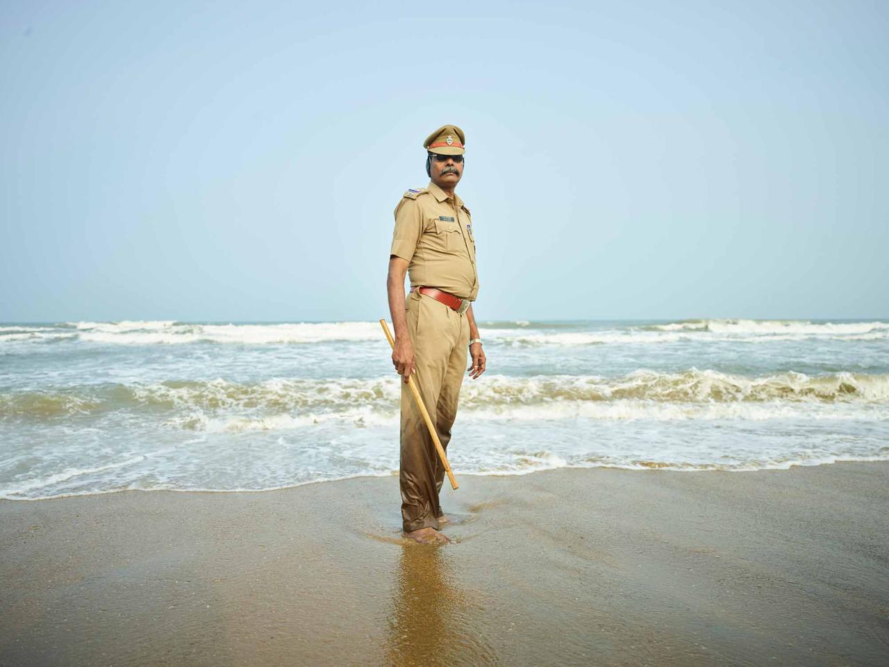 Ein indischer Polizist am Strand, mit Stock in der Hand. Ein indischer Polizist am Strand, mit Stock in der Hand.