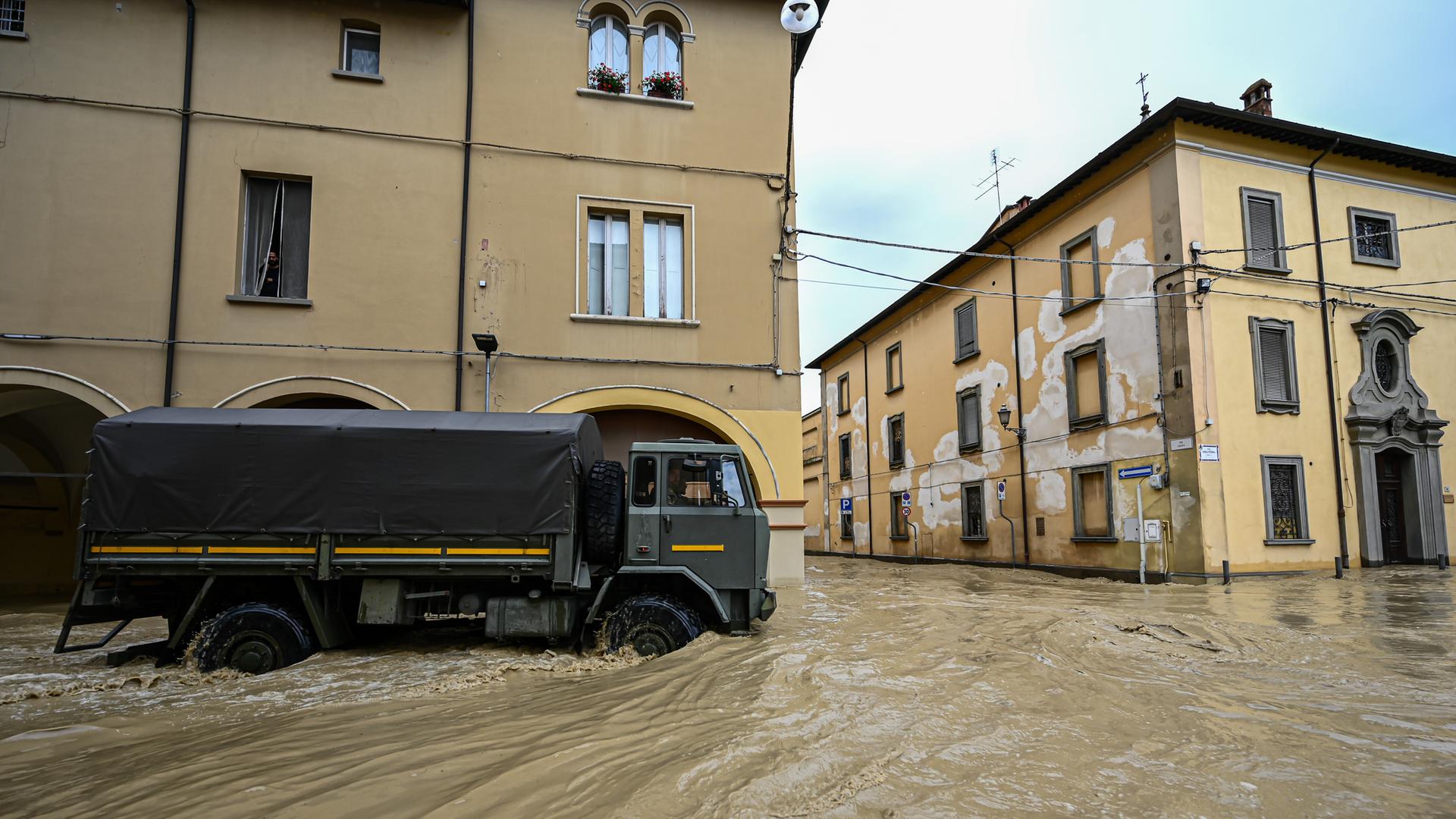 Ein dunkler Lkw fährt in einer Stadt durch überschwemmte Straßen