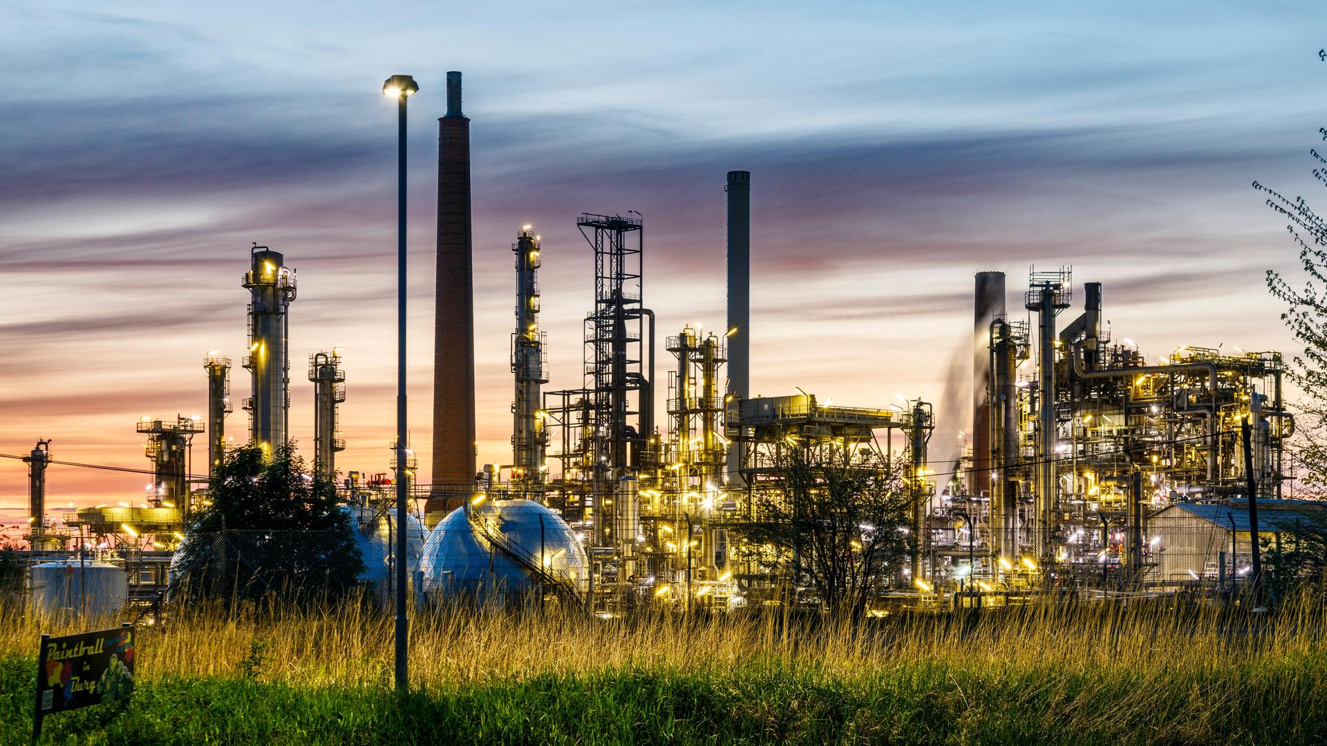 Die Raffinerie Heide GmbH mit beleuchteten Türmen und Industrieanlagen im Abendlicht. Die Raffinerie Heide GmbH mit beleuchteten Türmen und Industrieanlagen im Abendlicht.