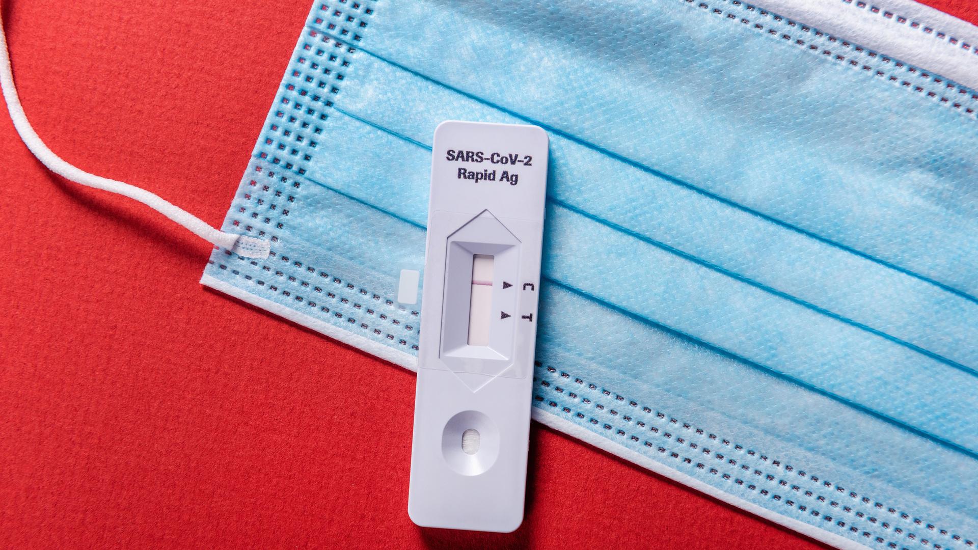 Ein negativer SARS-COV-2 Rapid Antigen Test liegt auf einer OP-Maske Ein negativer SARS-COV-2 Rapid Antigen Test liegt auf einer OP-Maske