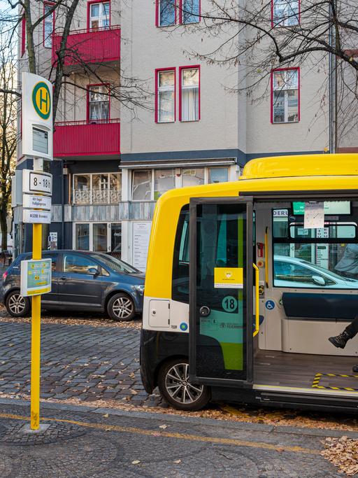 Ein autonomer Testbus der Berliner Verkehrsbetriebe mit geöffneter Tür an einer Haltestelle.