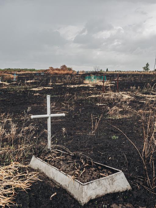 Ein Grab mit einem Kreuz im Kampfgebiet im Osten der Ukraine 