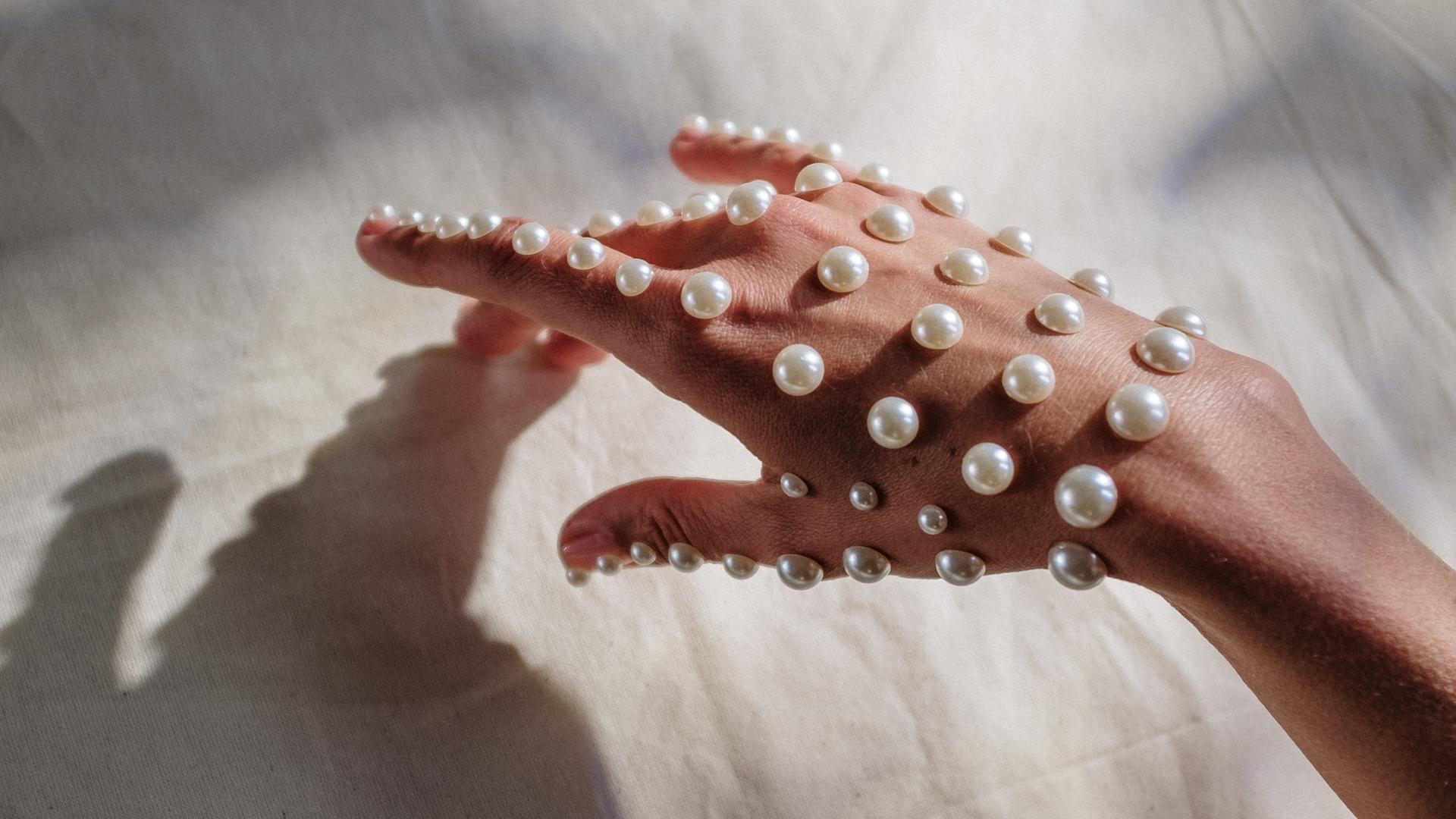 Eine mit Perlen beklebte Hand. Eine mit Perlen beklebte Hand.