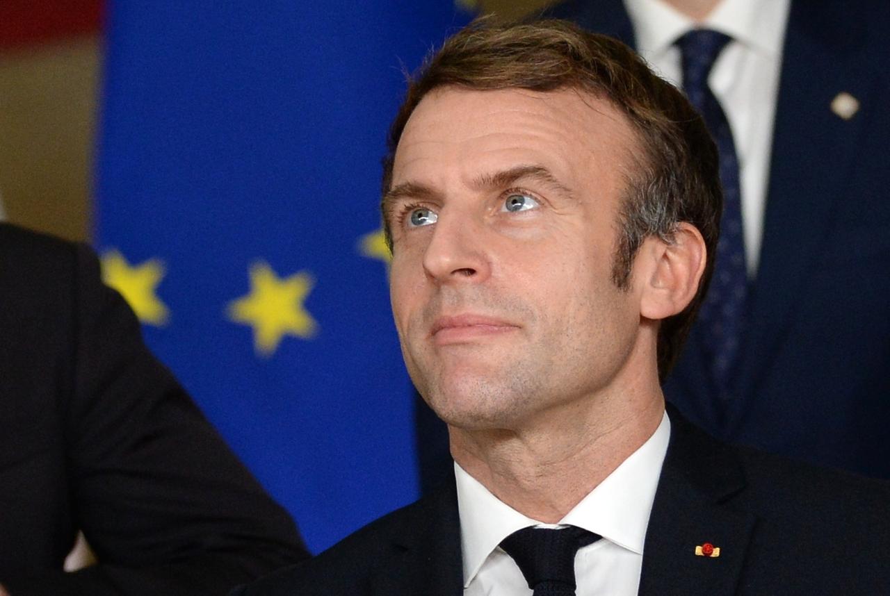 Frankreichs Präsident Emmanuel Macron bei einem Besuch in Brüssel. Im Hintergrund eine blaue Europa-Fahne, der Präsident blickt in richtung Himmel