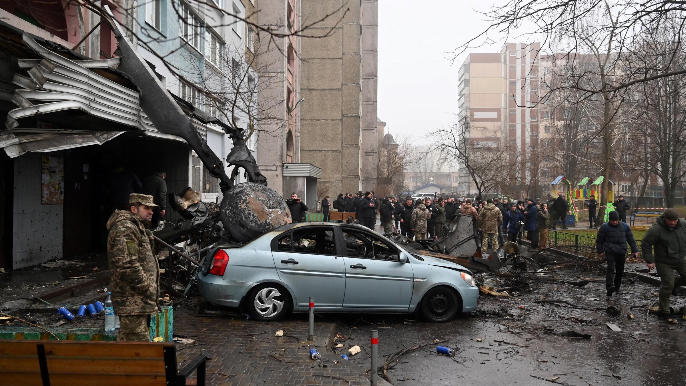 Kiew, Browary: Bei einem Hubschrauberabsturz in der Nähe eines Kindergartens sind mindestens 16 Menschen ums Leben gekommen. Unter ihnen der Innenminister Monastyrskyj. Menschen stehen am Unglücksort. 
