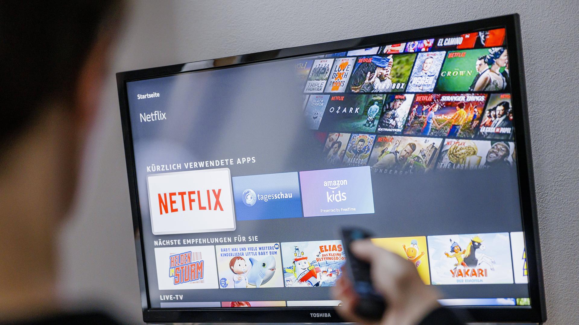 Auf einem TV-Bildschirm sind Logos von Medienplattformen zu sehen, darunter hervorgehoben dasjenige von Netflix. Auf einem TV-Bildschirm sind Logos von Medienplattformen zu sehen, darunter hervorgehoben dasjenige von Netflix.