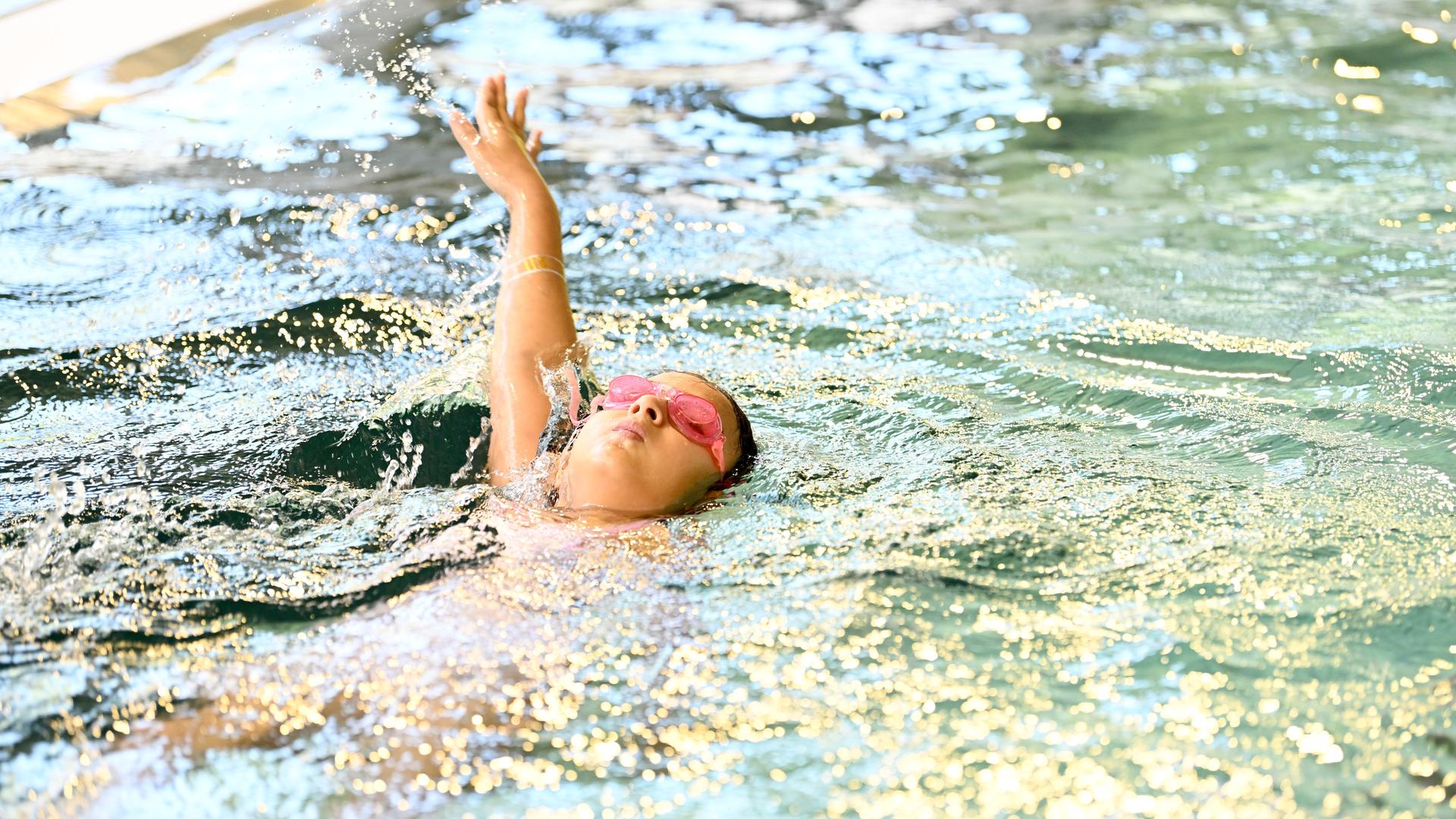 Ein Kind schwimmt auf dem Rücken im Schwimmbad. Ein Kind schwimmt auf dem Rücken im Schwimmbad.
