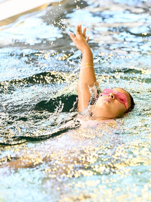 Ein Kind schwimmt auf dem Rücken im Schwimmbad. 