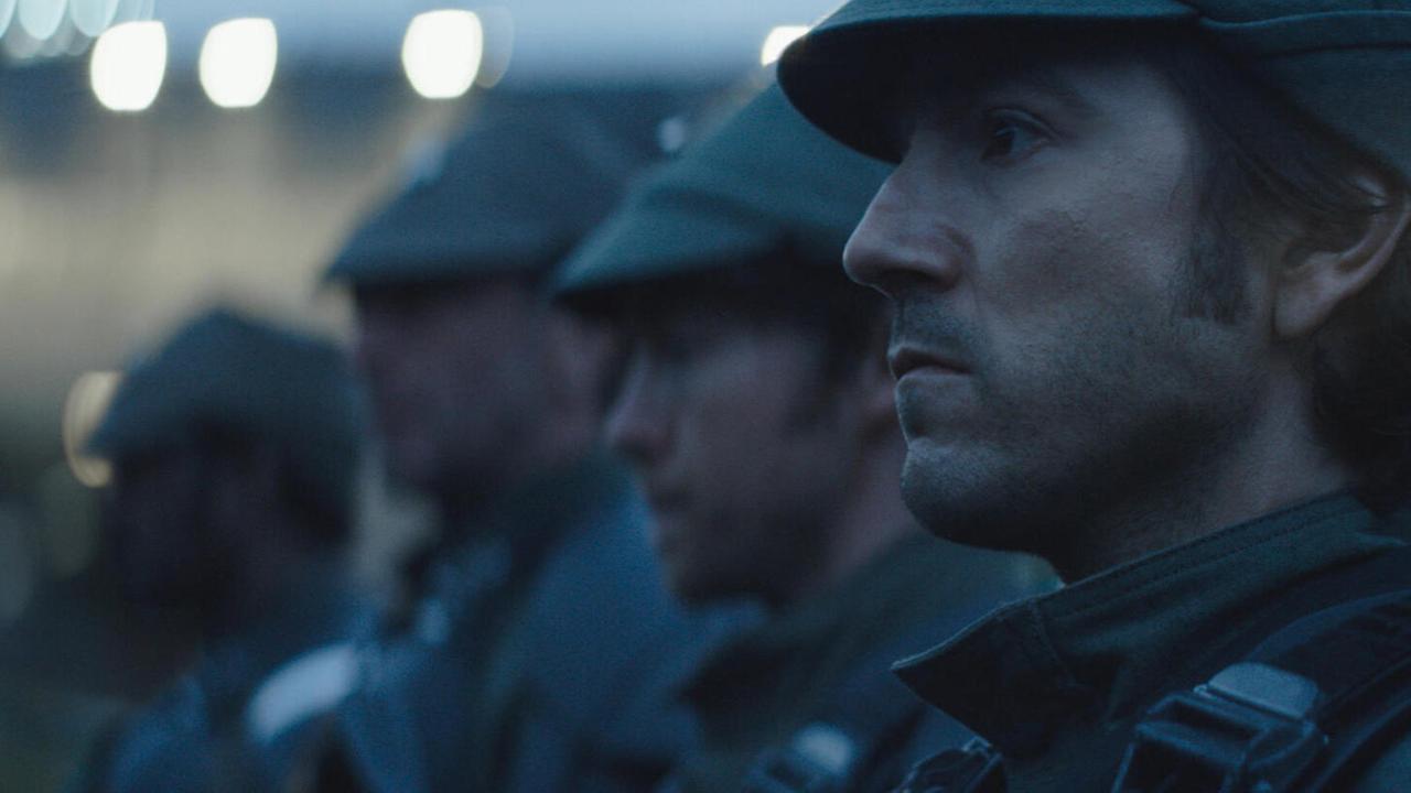 Im Still aus "Andor" ist Diego Luna in einer Großaufnahme im Profil zu sehen. Er scheint gemeinsam mit Soldaten in Reih und Glied zu stehen.