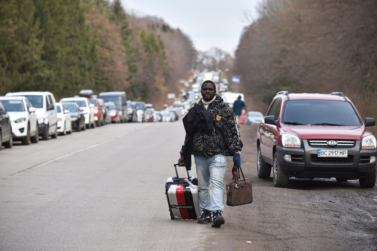 Ein Flüchtling läuft eine Straße entlang, an der Seite eine lange PKW-Schlange (1. März 2022)