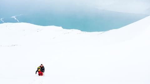 Weiße Schneelandschaft in der Arktis, darin ein Mensch.