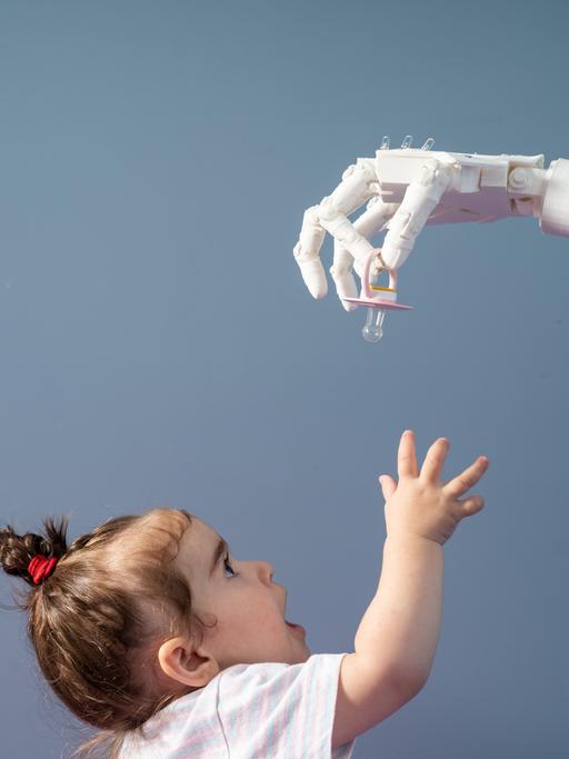 Eine humanoide Roboterhand gibt einem Baby einen Schnuller.