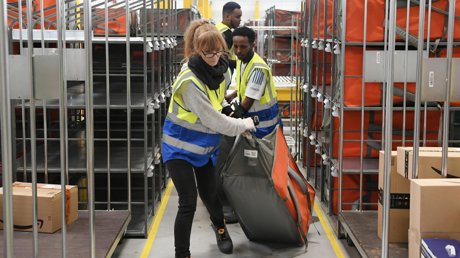 Mitarbeiter im Amazon-Verteilzentrum in Großebersdorf schleppen Pakete durch die Gänge. Mitarbeiter im Amazon-Verteilzentrum in Großebersdorf schleppen Pakete durch die Gänge.