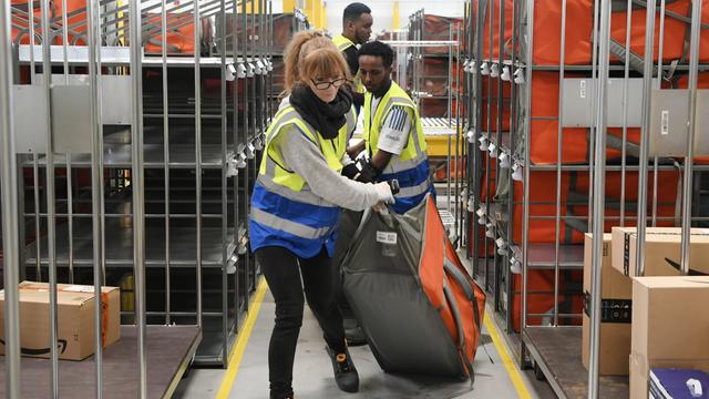 Mitarbeiter im Amazon-Verteilzentrum in Großebersdorf schleppen Pakete durch die Gänge.