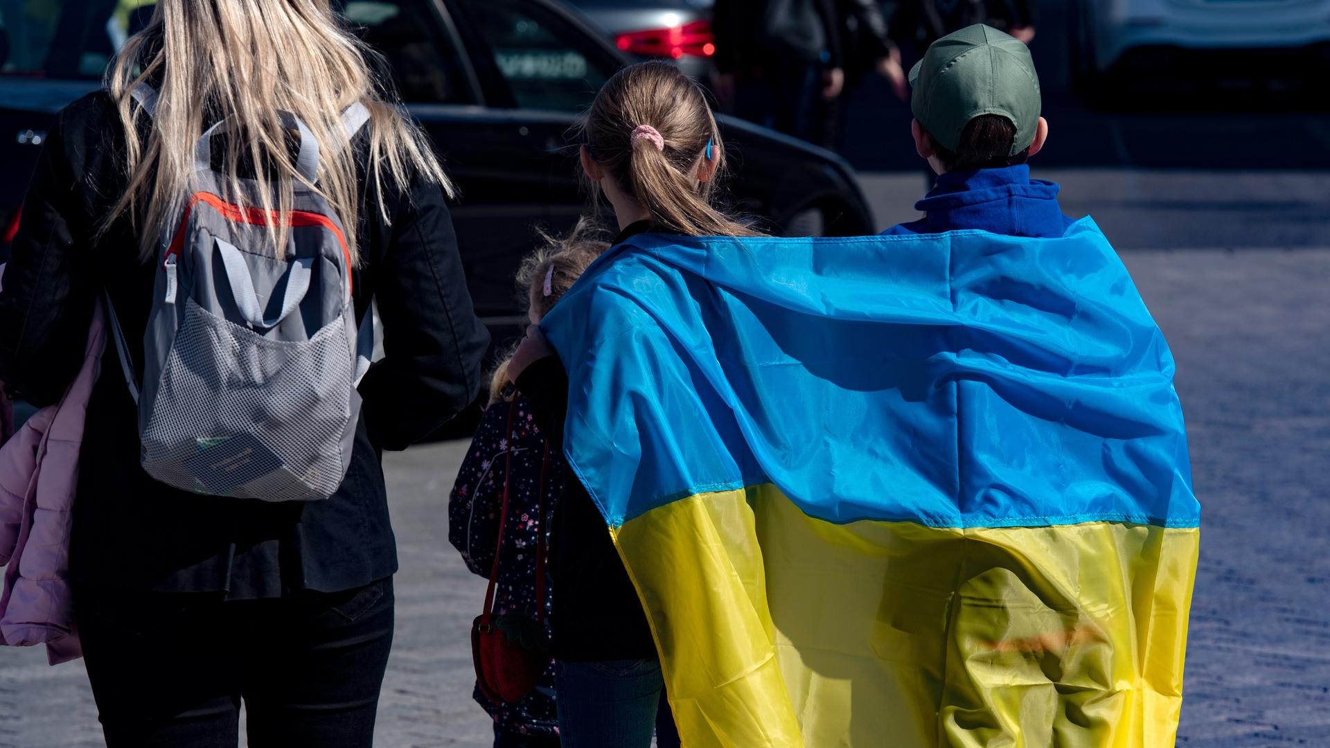 In der ukrainischen Fahne gehüllt gehen Kinder über den Pariser Platz in Berlin.